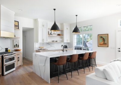 Modern kitchen with a white marble island, black pendant lights, and wood accents